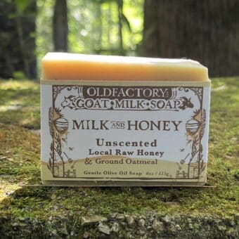 Box of Old Factory Goat Milk Soap labeled Milk and Honey, Unscented, with oats and olive oil soap packaging visible outdoors.